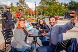 President Koppell taking selfie with students and crew members while filming The College Tour